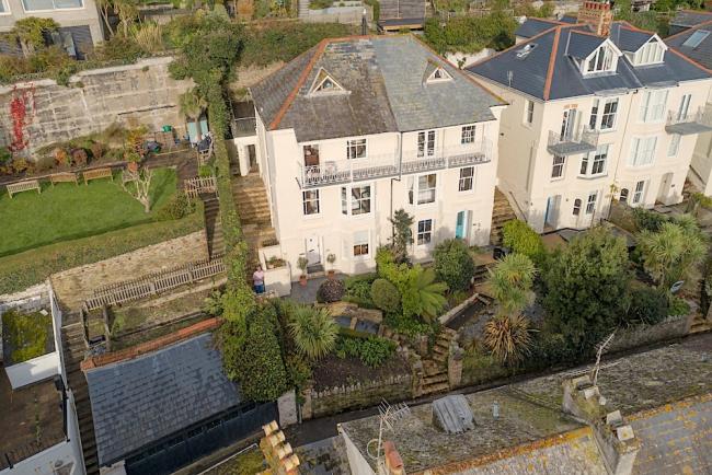 A semi-detached, 4-storey holiday home with a full-width shaded balcony overlooks the waterside.