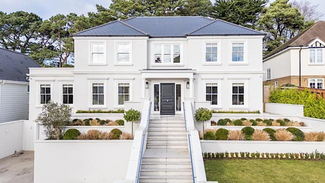 An elevated, contemporary house approached by a line of steps overlooks an ornamental garden.