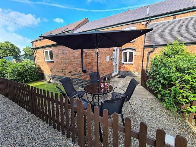 A brick-built Shropshire barn conversion overlooks a shrub-filled courtyard with a picket fence.