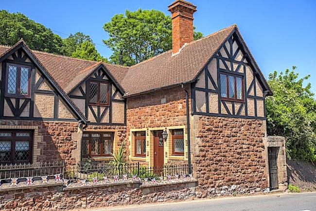 Exterior of a stone-built holiday cottage in Dunster with a secure front garden.