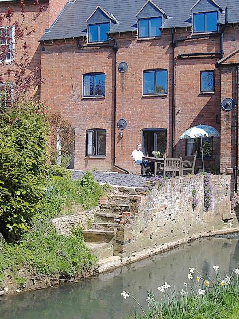 A 3-storey, brick-built mill conversion alongside the mill race.