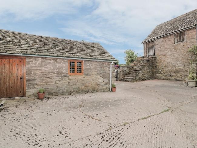 A single storey barn conversion stands on the edge of a paved courtyard.