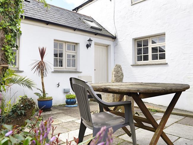 Whitewashed exterior of a Cornish cottage overlooking a courtyard.