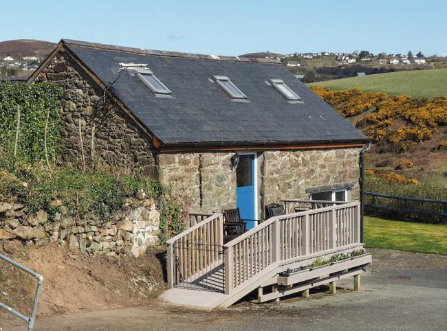 A stone-built barn conversion surrounded by open countryside with a ramp to the front door.