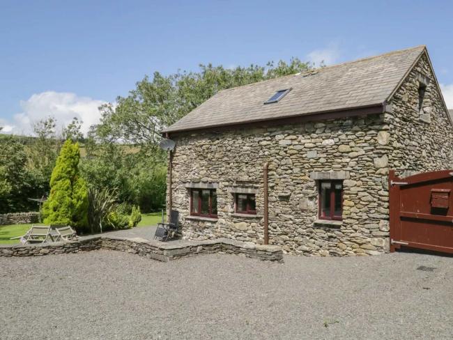 A garden table with a parasol sits outside a stone-built barn conversion in Cumbria.