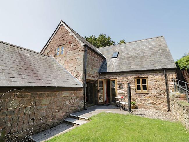 A stone-built holiday barn conversion overlooks a large lawn.