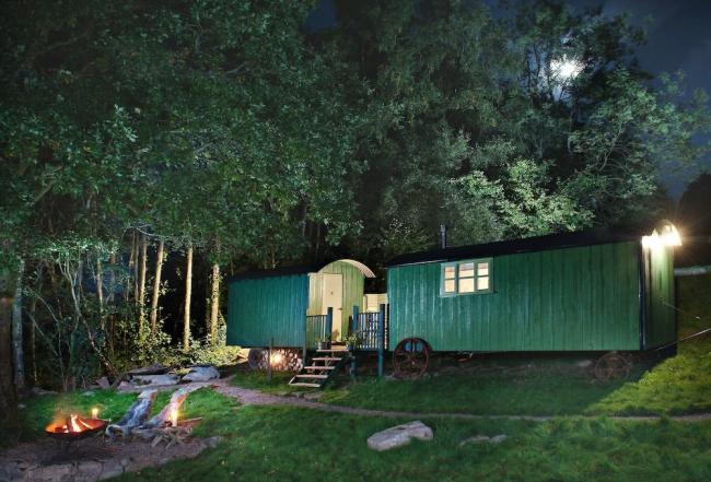 Two shepherd huts at dusk, converted and linked to form a single unit.