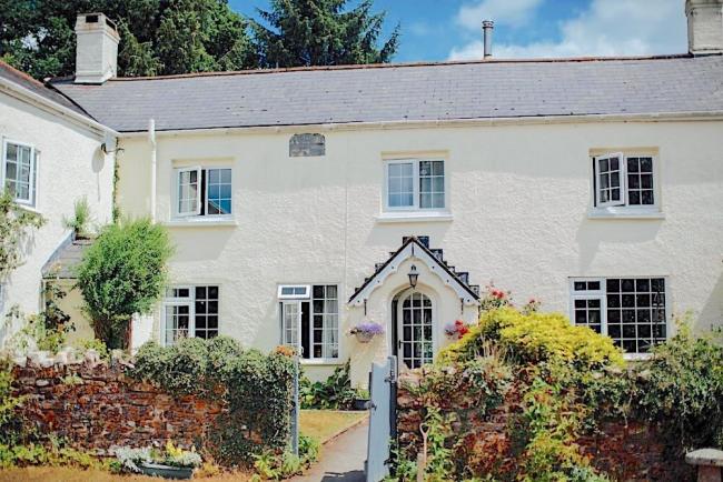 Large Exmoor farmhouse with cottage windows and a covered porch sits behind a walled front garden.