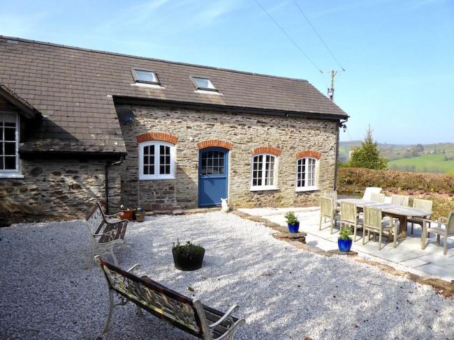 A Countryside barn conversion overlooks a courtyard with tables and chairs.