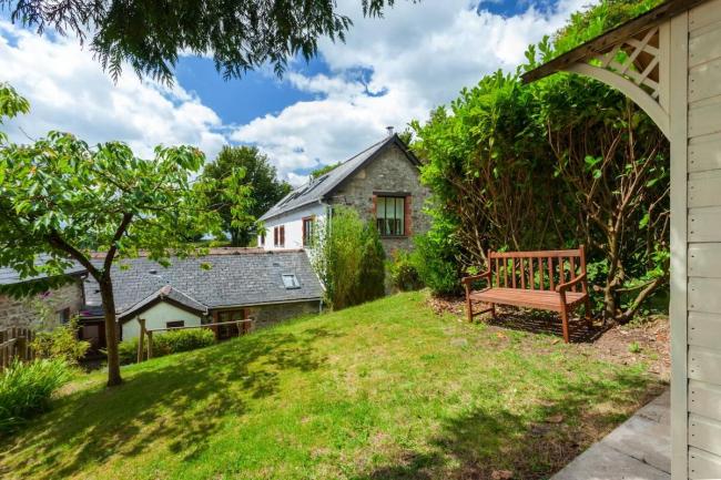 An Exmoor holiday cottage nestles below a lawn that slopes down to it.