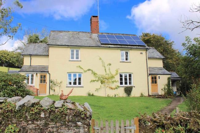 A country cottage overlooks a walled lawn garden.