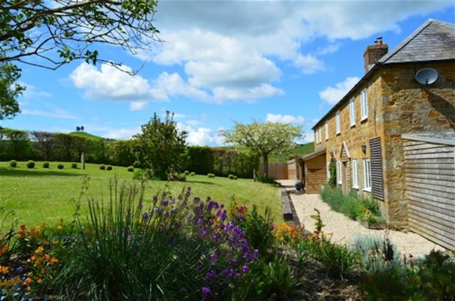 Side view of a long farmhouse and large lawn.