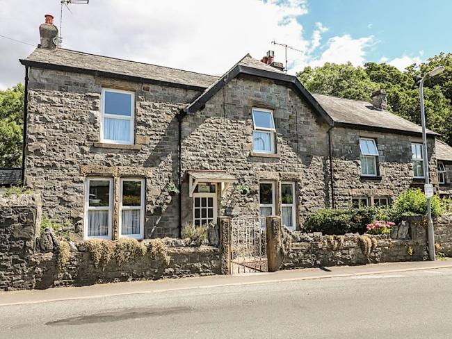 Stone-built Cumbrian holiday cottage with a front garden behind a low stone wall.