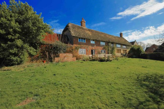 Large thatched farmhouse overlooks a spacious lawn