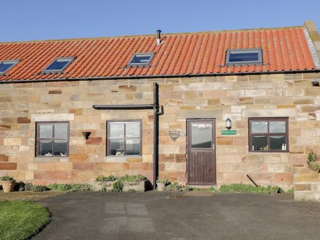 Stone built Whitby holiday home with terracotta tiles and Velux windows on the roof overlook a lawn and parking space