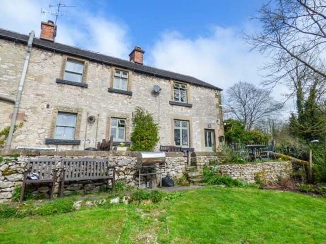 Large stone-built rural cottage exterior with a spacious lawn.