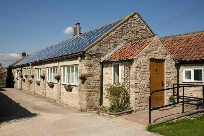 Exterior of a long, many-windowed barn conversion to form a single-storey holiday cottage in Pickering.