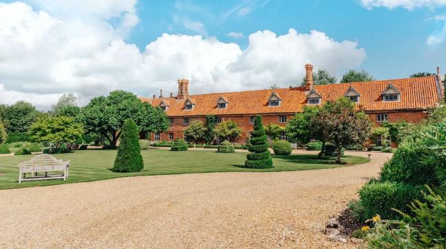 A terraced row of Norfolk cottages with flower-filled front gardens.