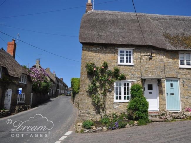 Exterior of a stone-built thatched cottage in Dorset.