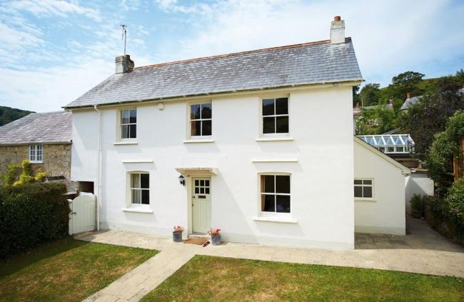 A double-fronted East Devon holiday cottage in front of a secure lawned garden.