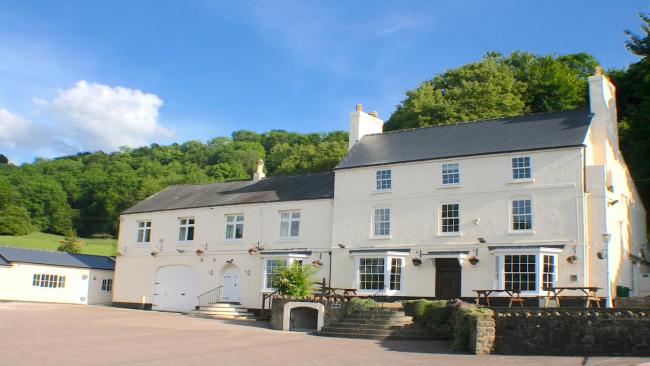 Exterior of a large double-fronted Georgian House with bay windows and an adjoining wing.