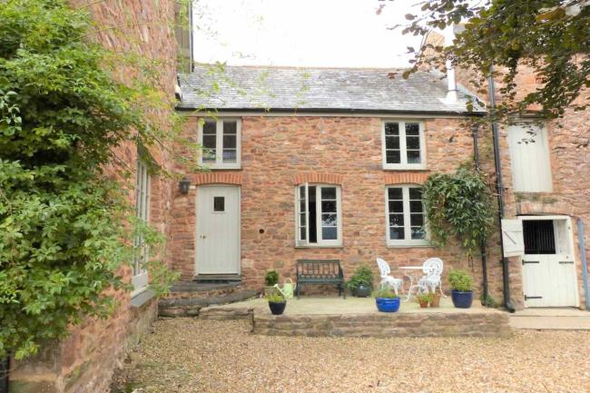 Stone-built terraced farm cottage in Somerset overlooking a courtyard.