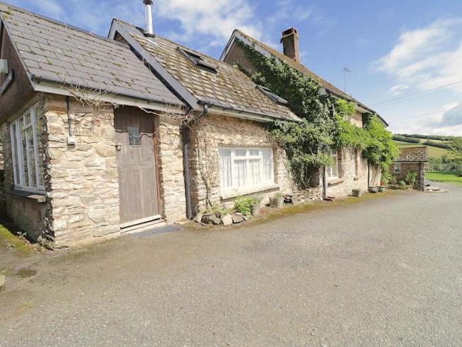 A wisteria-clad, stone-built Withypool holiday cottage with oak front door.