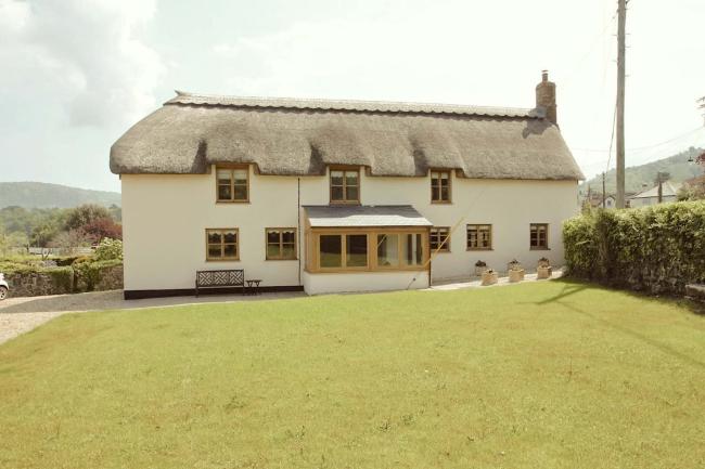 thatched Somerset country cottage overlooks a large lawn.