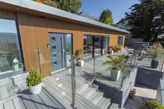 Exterior of a luxury Minehead lodge with bi-fold glass dors and a spacious deck.o