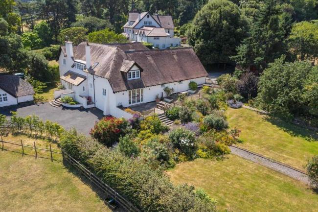 Aerial view of a large holiday cottage on the Somerset coast surrounded by gardens.