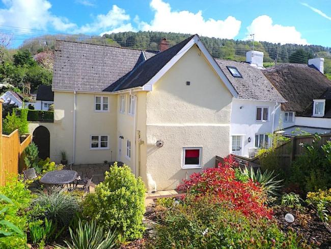 Exterior of an East Devon coastal cottage with a patio and a well-kept garden.