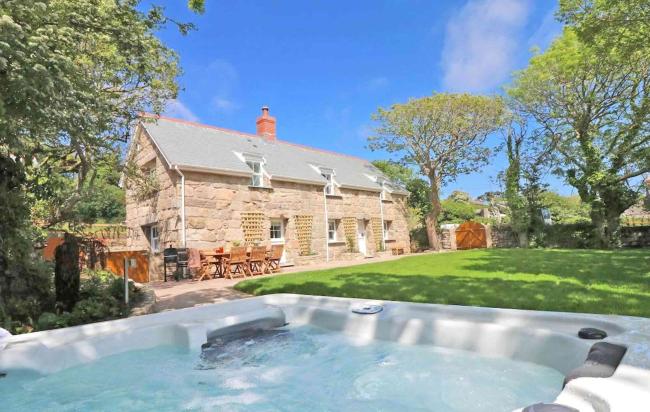 Large, stone-built Cornish cottage overlooks a garden with a hot tub.