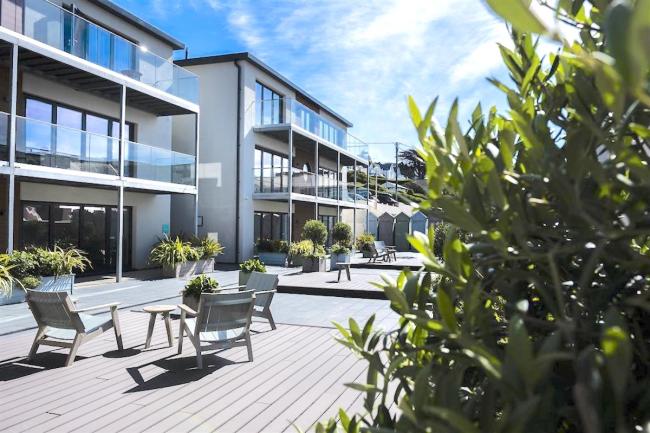 3-storey contemporary seaside apartment block with glass-screened balconies.