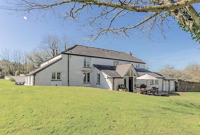 An extended farmhouse holiday cottage overlooks an expansive lawn.