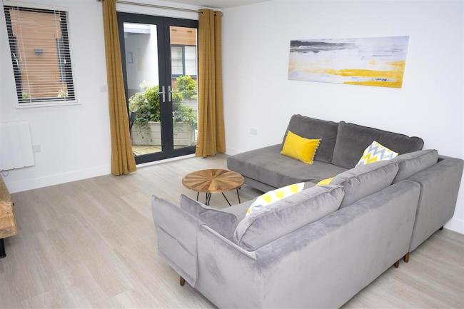 L-shaped sofa with cushions and coffee table in a stylish lounge with French windows to a balcony.