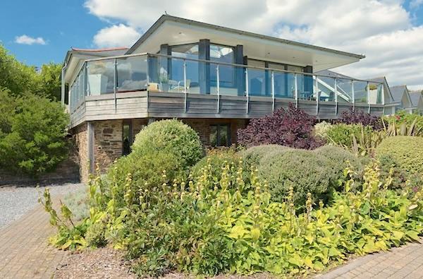 A contemporary wood and glass bungalow with a wrap-around deck overlooks a shrub-filled garden.