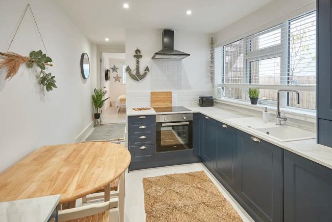 A stylish galley kitchen with fitted flor units, breakfast table and integrated appliances