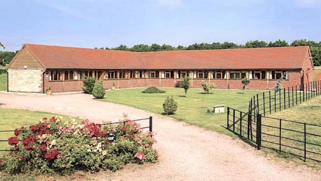 A large L-shaped single-storey holiday lodge surrounded by lawns.