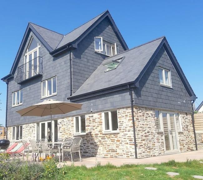 A large, 3-storey detached house built of stone with a 1st floor clad in slates.