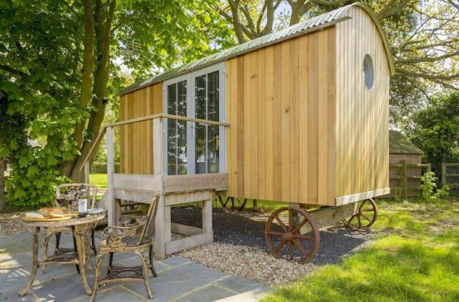 Herefordshire Shepherds Hut is shaded by trees in a garden.