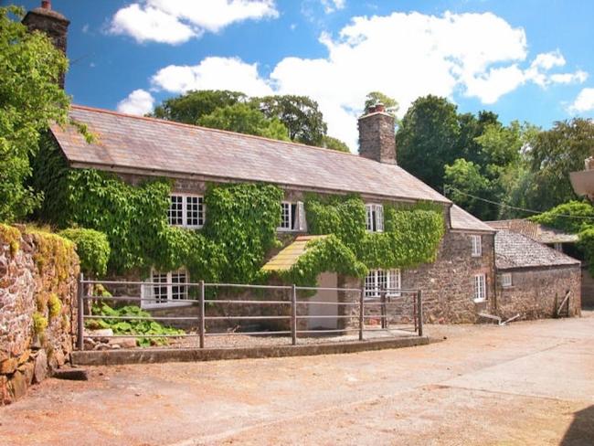 Exterior of a bushy, ivy-clad Dartmoor farmhouse.