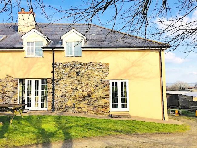 Exterior of a stout North Devon farm cottage overlooking a garden.