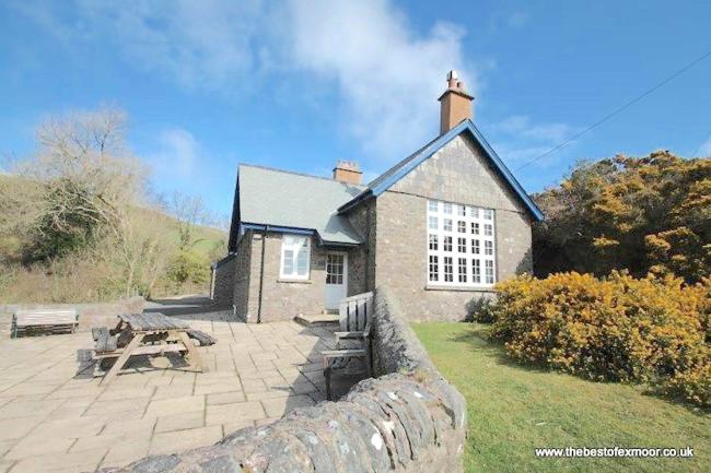 A converted stone-built, remote Exmoor schoolhouse with a lawn and large patio.
