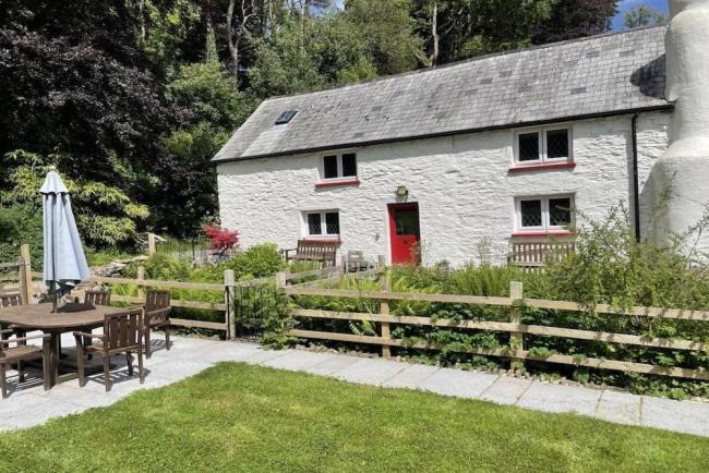 The exterior of a stone-built country cottage overlooks a pretty garden.