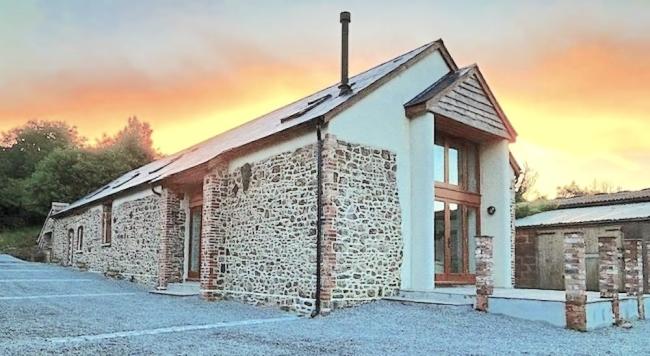 A Devon barn conversion with a deck at sunset.