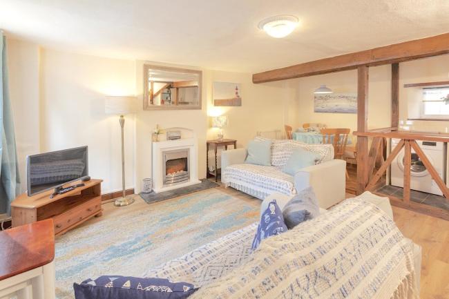A lounger with two matching sofas facing a widescreen TV and open fire with gas-flame effect.