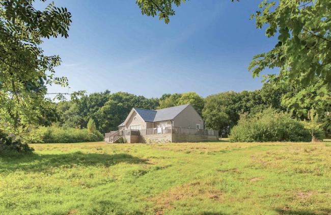 A single-storey eco-lodge surrounded by a deck and open fields.