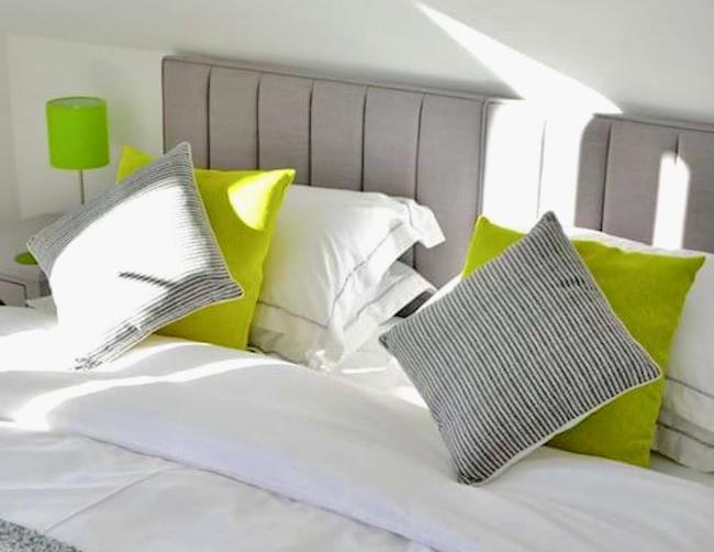 A double bed with pillows, scatter cushions, bedside tables an lamps.