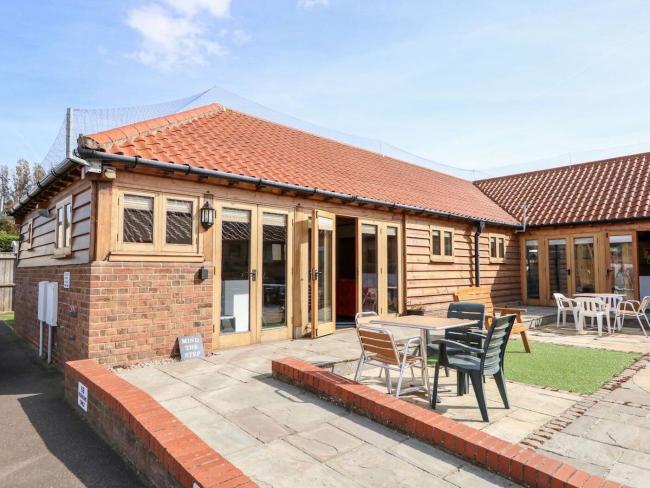 Exterior of an L-shaped holiday bungalow in Hunstanton overlooking a paved courtyard giving level access to the house