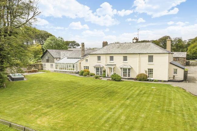 Exterior of a 2-storey country house on Exmoor overlooking a large lawn with a hot tub.